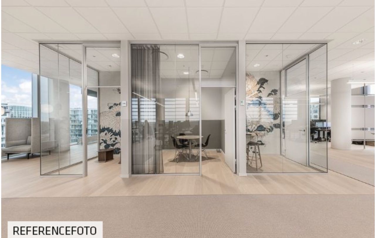 Moderne kontor med glasvægge og et rundt bord med stole i en åben, lyse hall med udsigt til byen