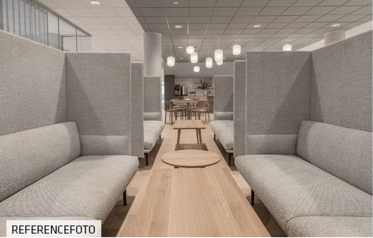 Moderne kontor med højloftede lokaler, lyse loftslamper og brune trægulve med moderne møbler og sofaer