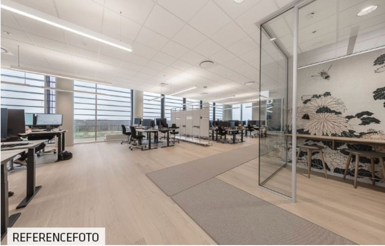 Kontor med moderne indretning, højt til loftet og glasvægge. Store vinduer med udsigt til byen, hvide lofter og masser af