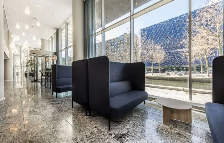 Moderne lobby med slanke sofaer, bord og gulvbelægning samt glasvinduer med udsigt til byen