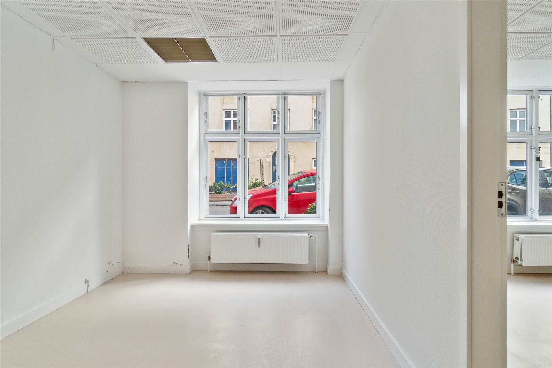 Lys kælder med 331 m², fem kontorer, hvide vægge, hvide gulve, store ruder, radiatorer og en åben dør.