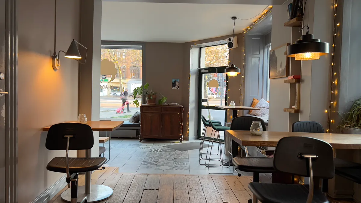 Inde i caféen er der to lange træborde med stole og små lysekroner hængende over bordene