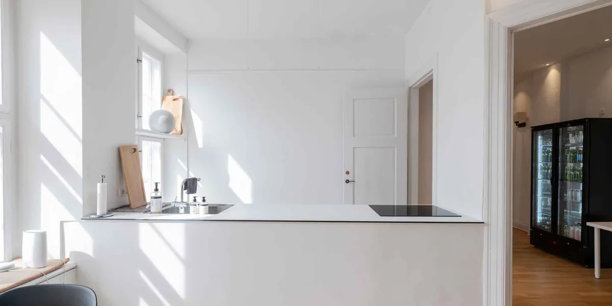 Køkken med induktionskomfur, hængende lysekroner, lysevinduer og en stor køleskab med døre