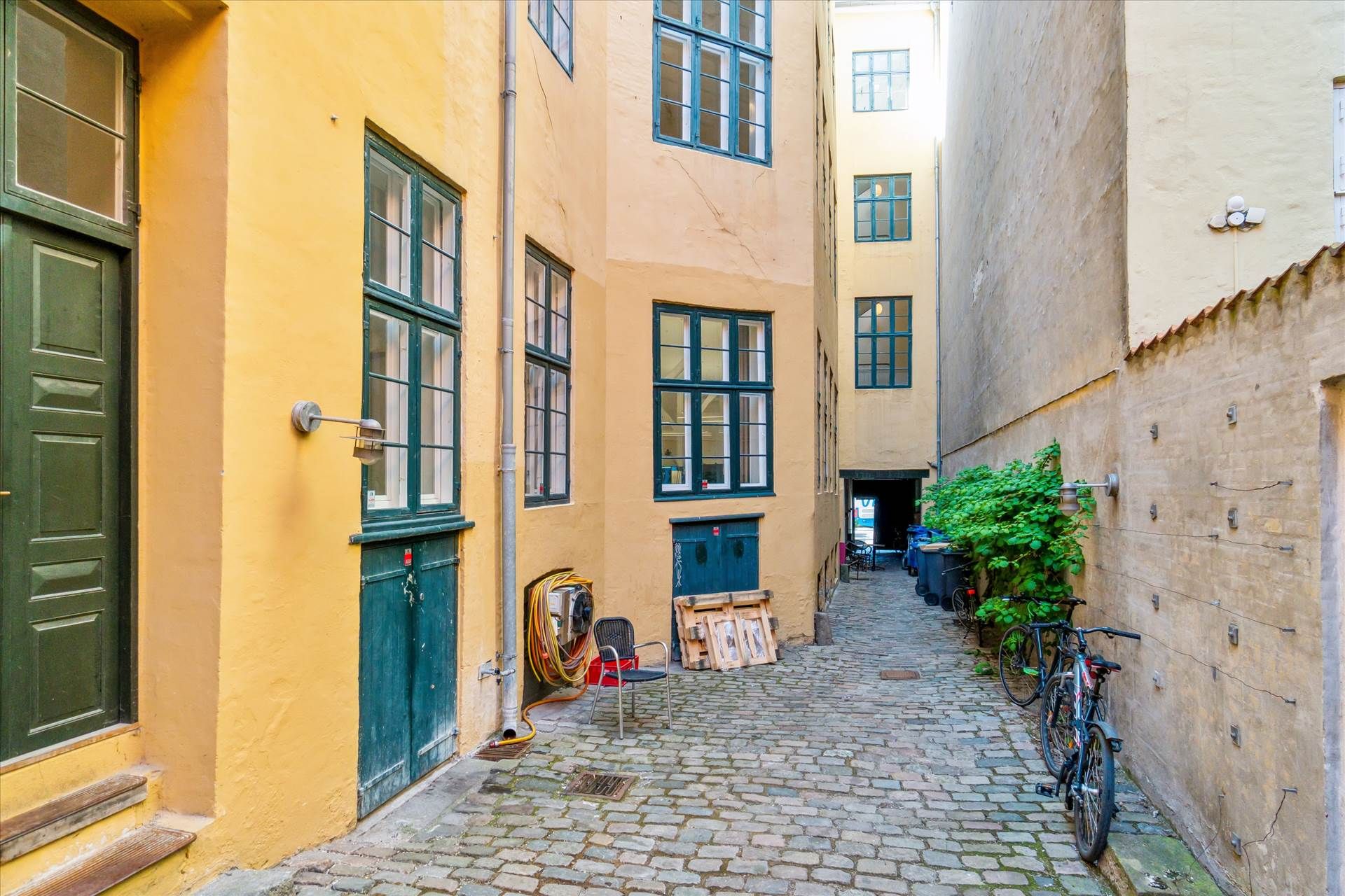 En gammel gade med to huse, to cykler, og en stol med nogle rør i nærheden