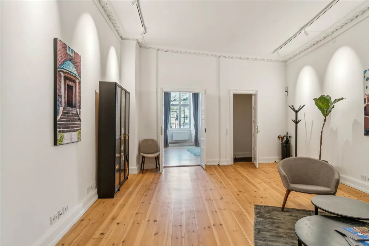 En stor, pænt indrettet stue med højkvalitets plankegulve og en stor stol med et bord i hjørnet