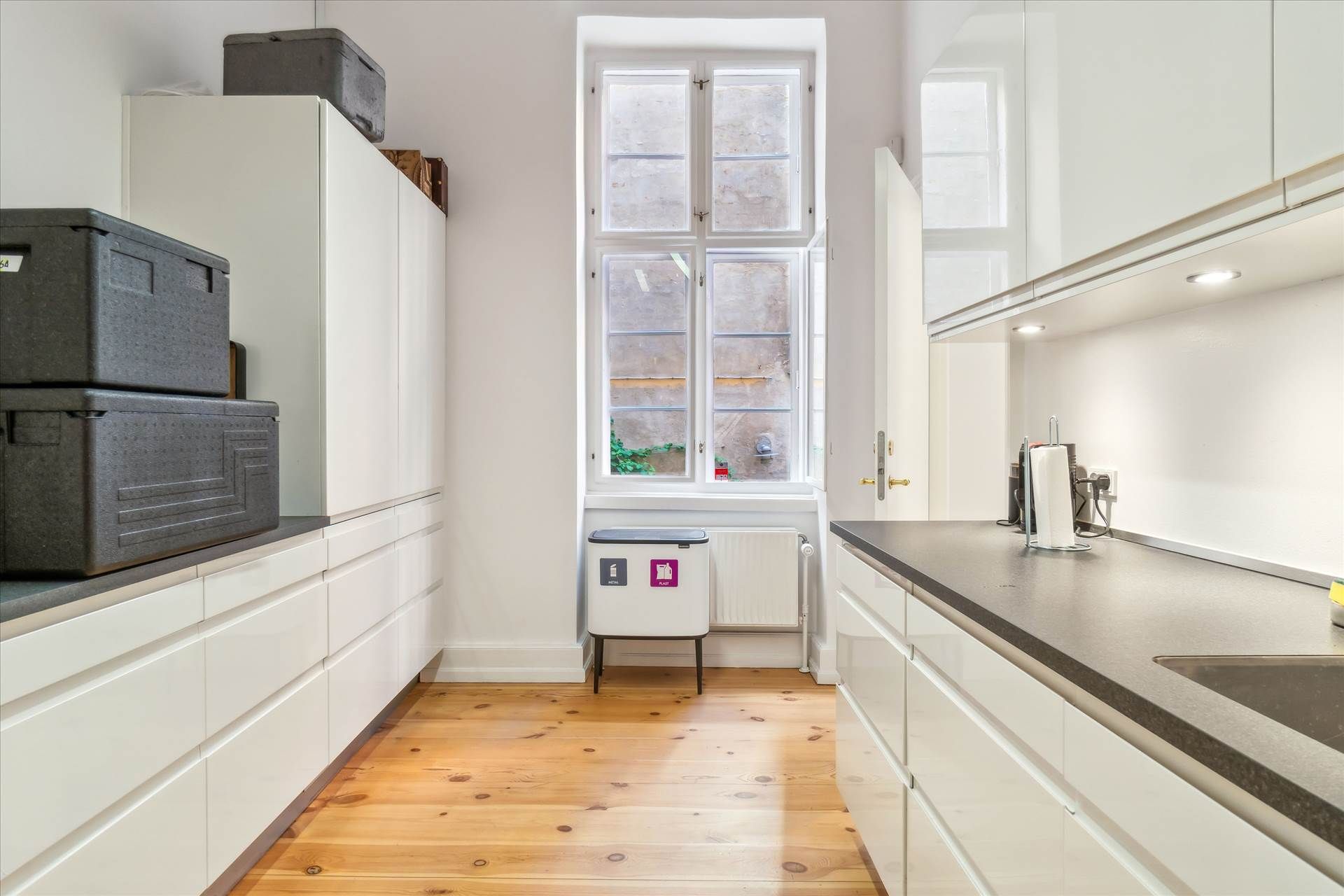 Lejlighed med høj kvalitet, moderne hvide køkkenskabe og en stor vinduesindgang med udsigt til gaden