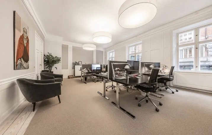 Moderne og pænt indrettet kontor med skriveborde, stolpelampe og møbler, alt i en flot oprindelig stil