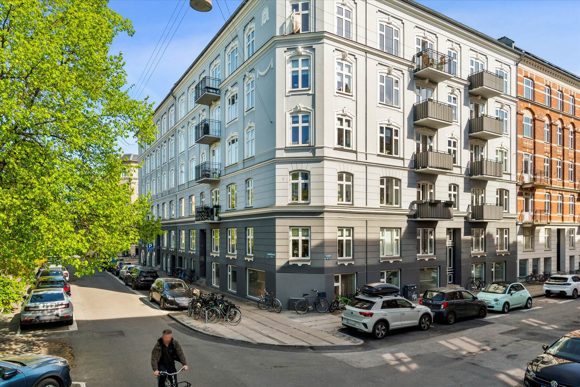 Man cykler på gaden med parkerede biler og stilleblik på baggrunden