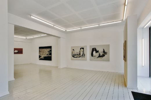 Hvidmalet showroom med lyse gulvplanker og tre store værker på væggen