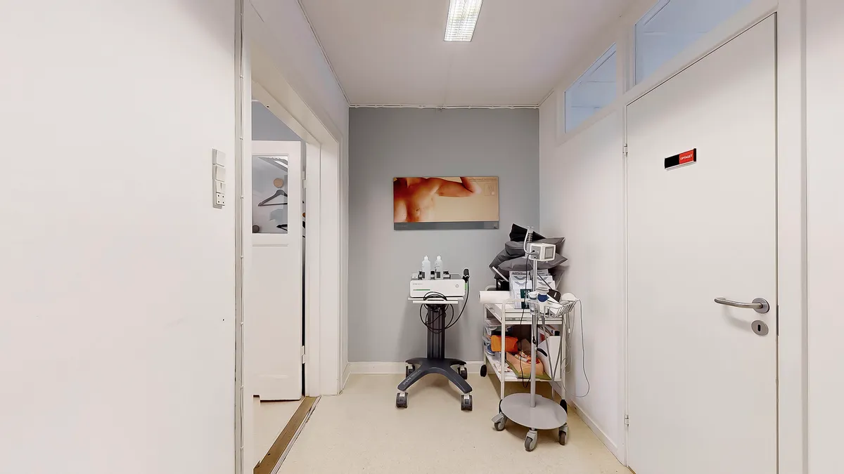 En hvid lægepraksis med et hvidt vægmaleri og en hvid dør, hvor der er udstyr og udstyr samt en kunstværk på væggen