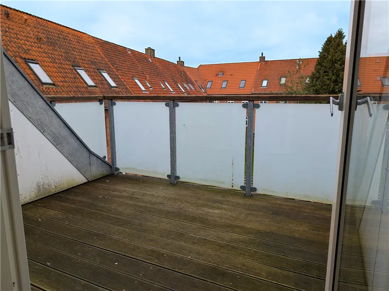 Balkon med udsigt til en række røde tagdækkede huse og et træ i forgrunden