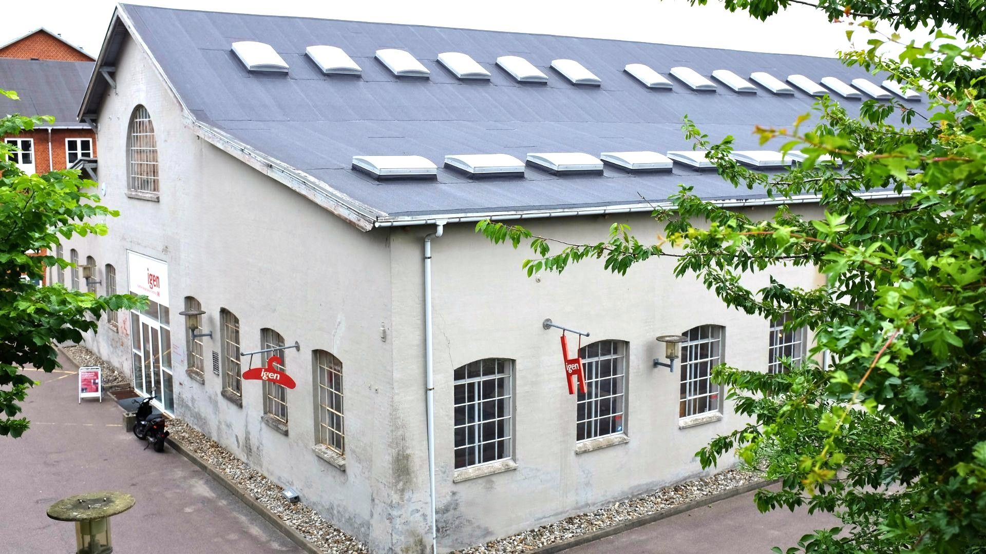 En bygning med et skilt med navnet Igen, røde hængere og solpaneler på taget
