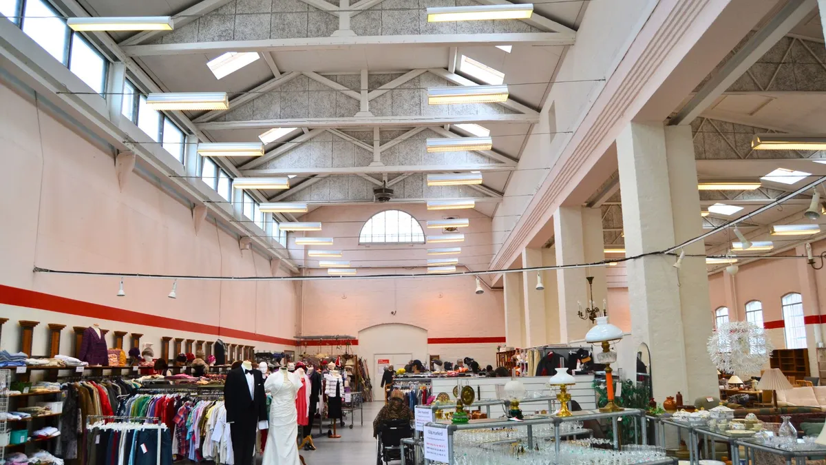 Butikslokale med hængende lysekroner og flere hylder med tøj og genstande til salg