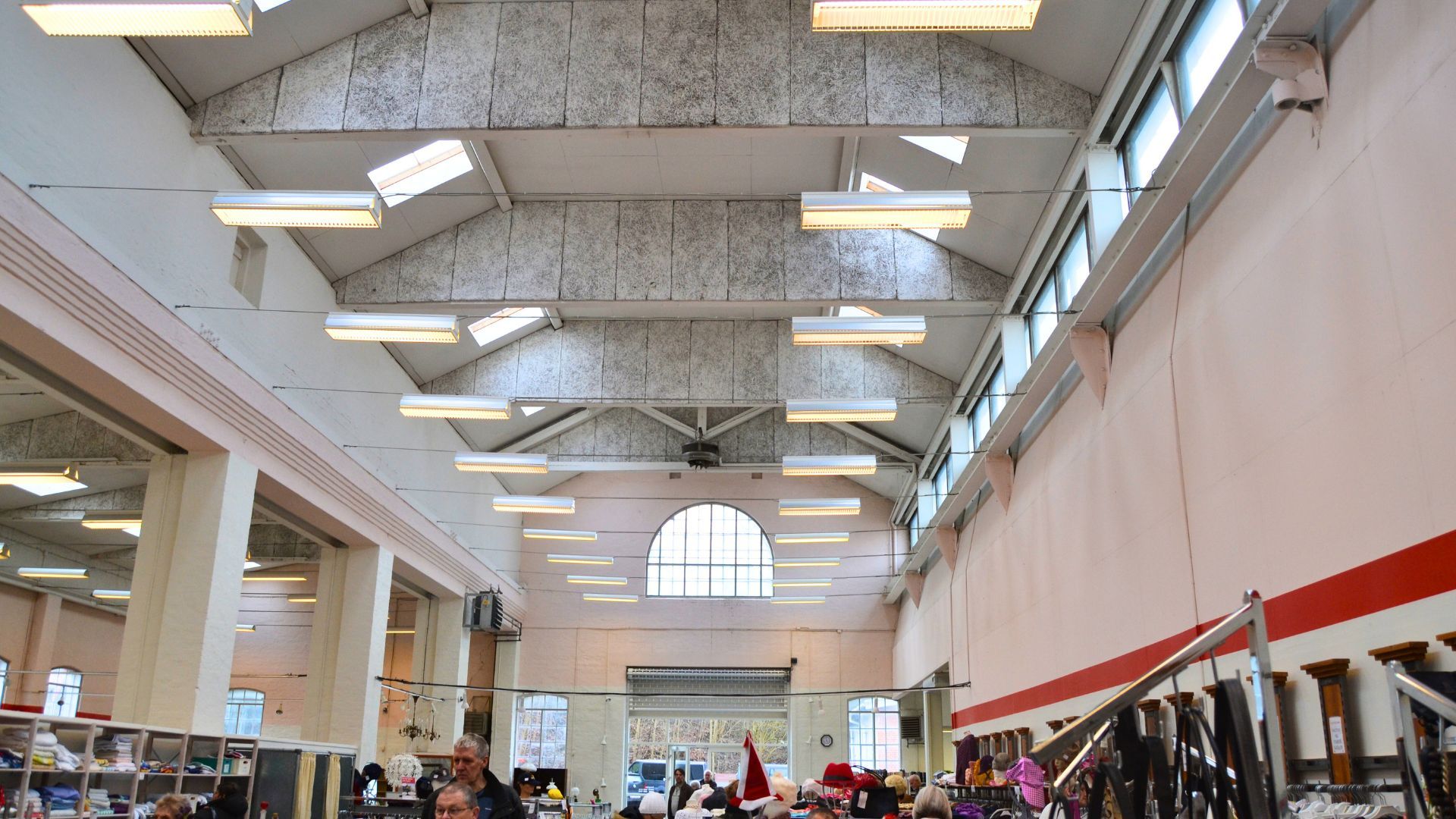 Foto af indvendig område i en stor butik med højt loft, lyse loftslamper, store vinduer og kunderne ser ud til at handle