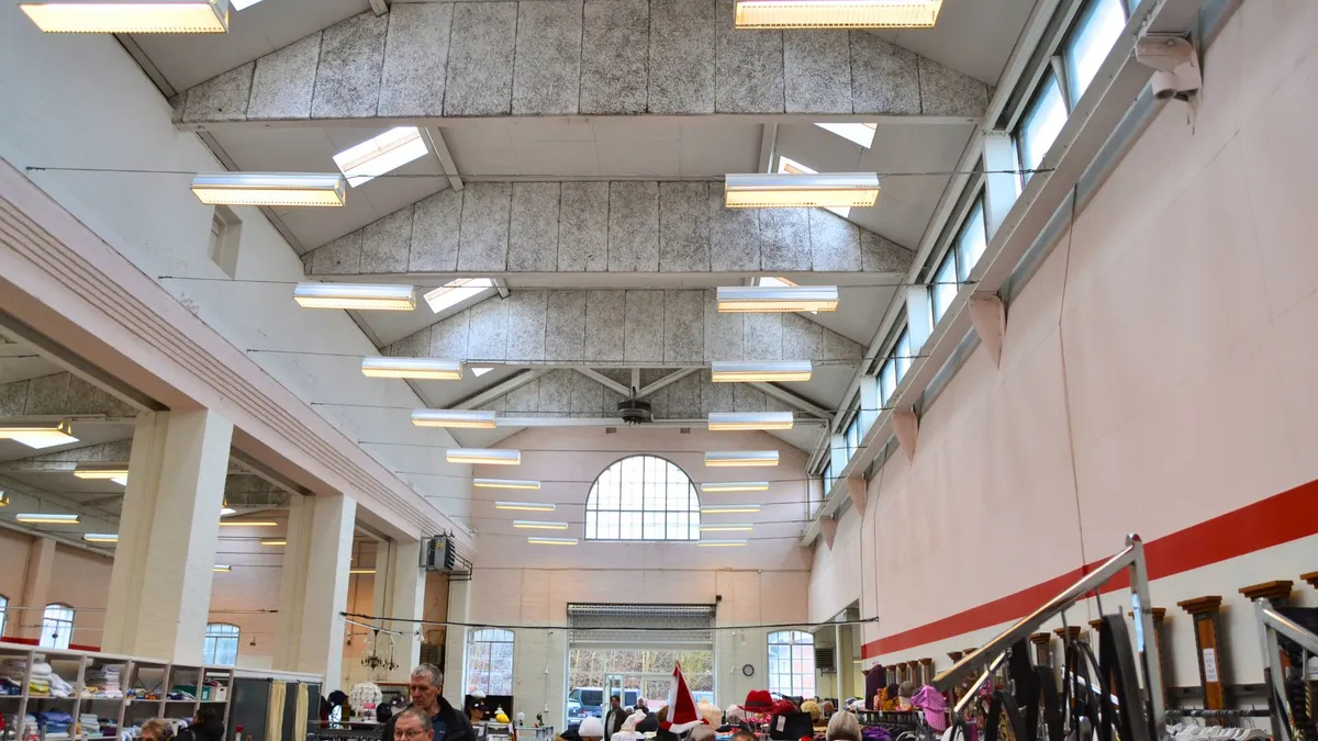 Foto af indvendig område i en stor butik med højt loft, lyse loftslamper, store vinduer og kunderne ser ud til at handle