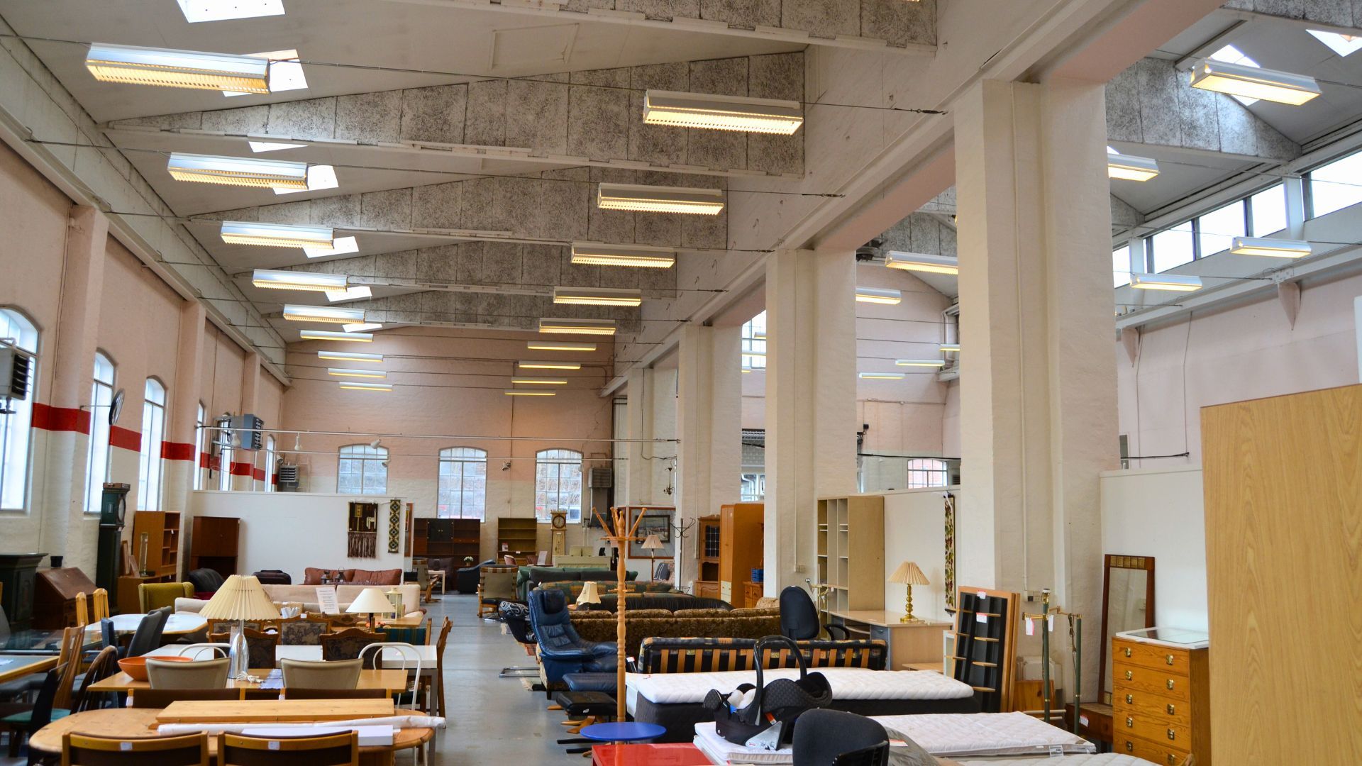 Stort lokale med møbler og inventar, hvilket inkluderer sofaer, stole, bord, lysekroner og vinduer