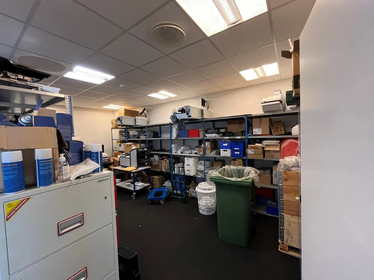 Kontor med lager og mødelokale med kassevogn, skraldespand, skraldekurve, papkasser og en printer