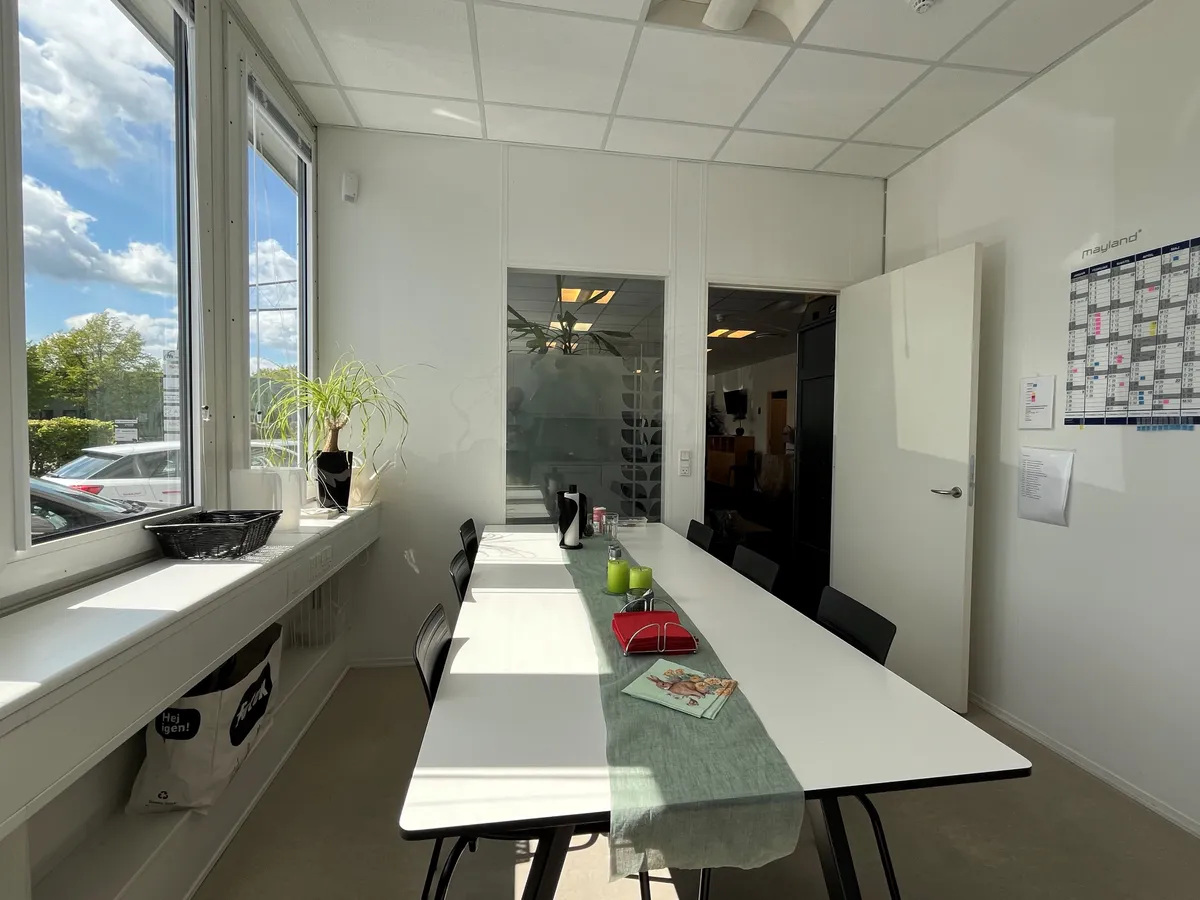 Kontorlokaler med mødelokale og lagerrum med plante, kalender og møbler i nærheden af vinduet