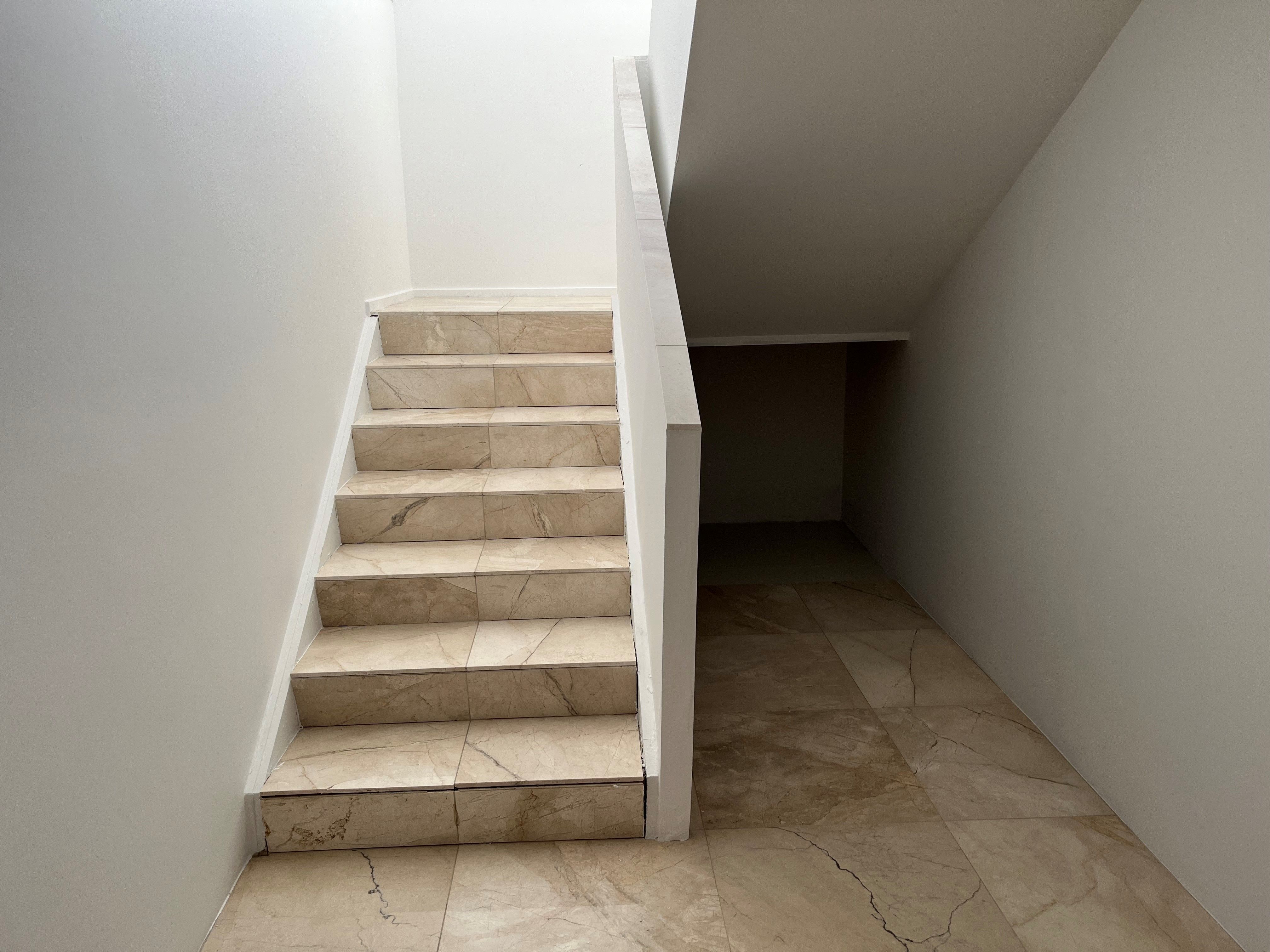 Marmortrapper fører ned til kælderen i et hvidt indre med marmorgulv og hvide vægge