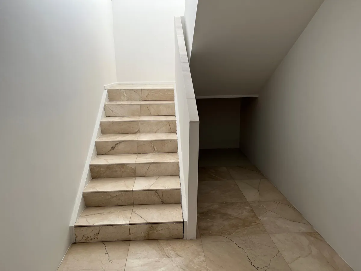 Marmortrapper fører ned til kælderen i et hvidt indre med marmorgulv og hvide vægge