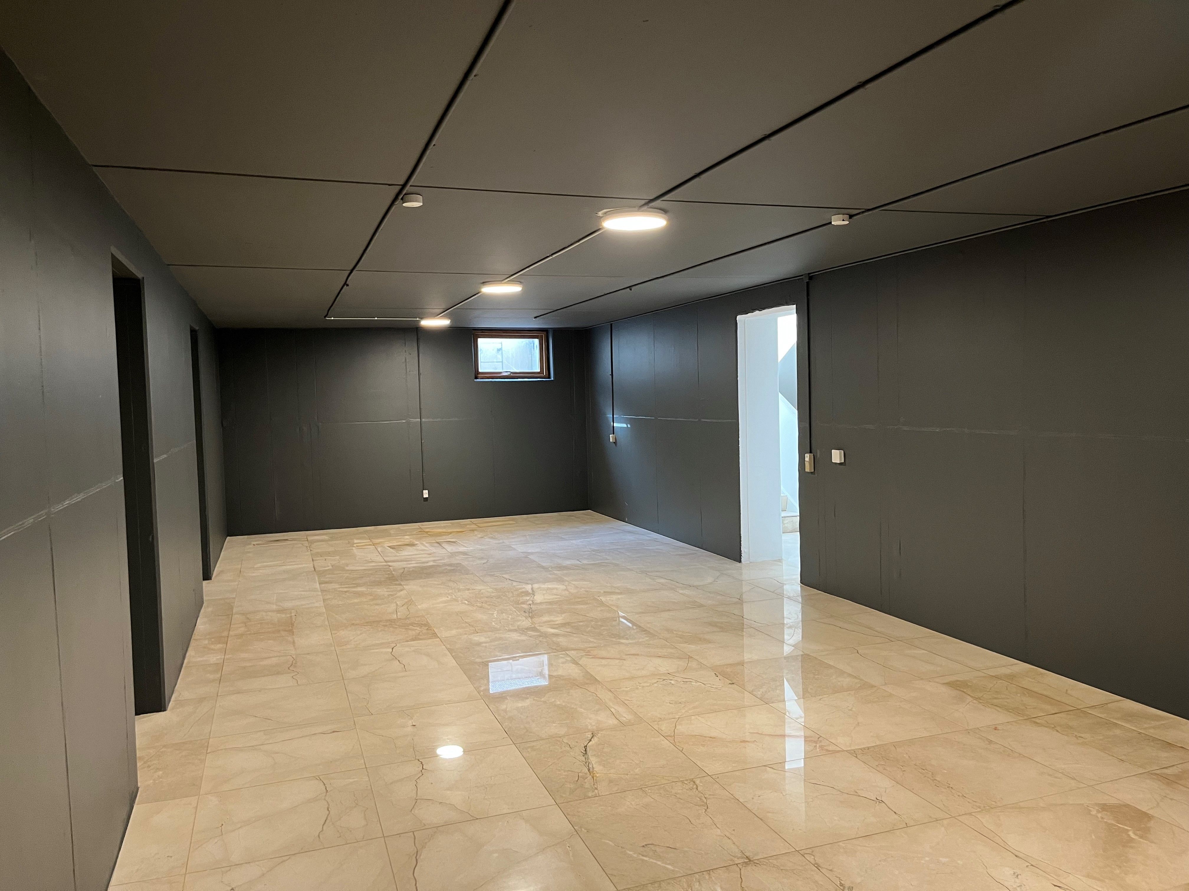 Marmorfliser og lyse loftslampepærer i det store kontor med nyt køkken og toilet