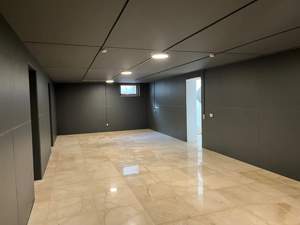 Marmorfliser og lyse loftslampepærer i det store kontor med nyt køkken og toilet