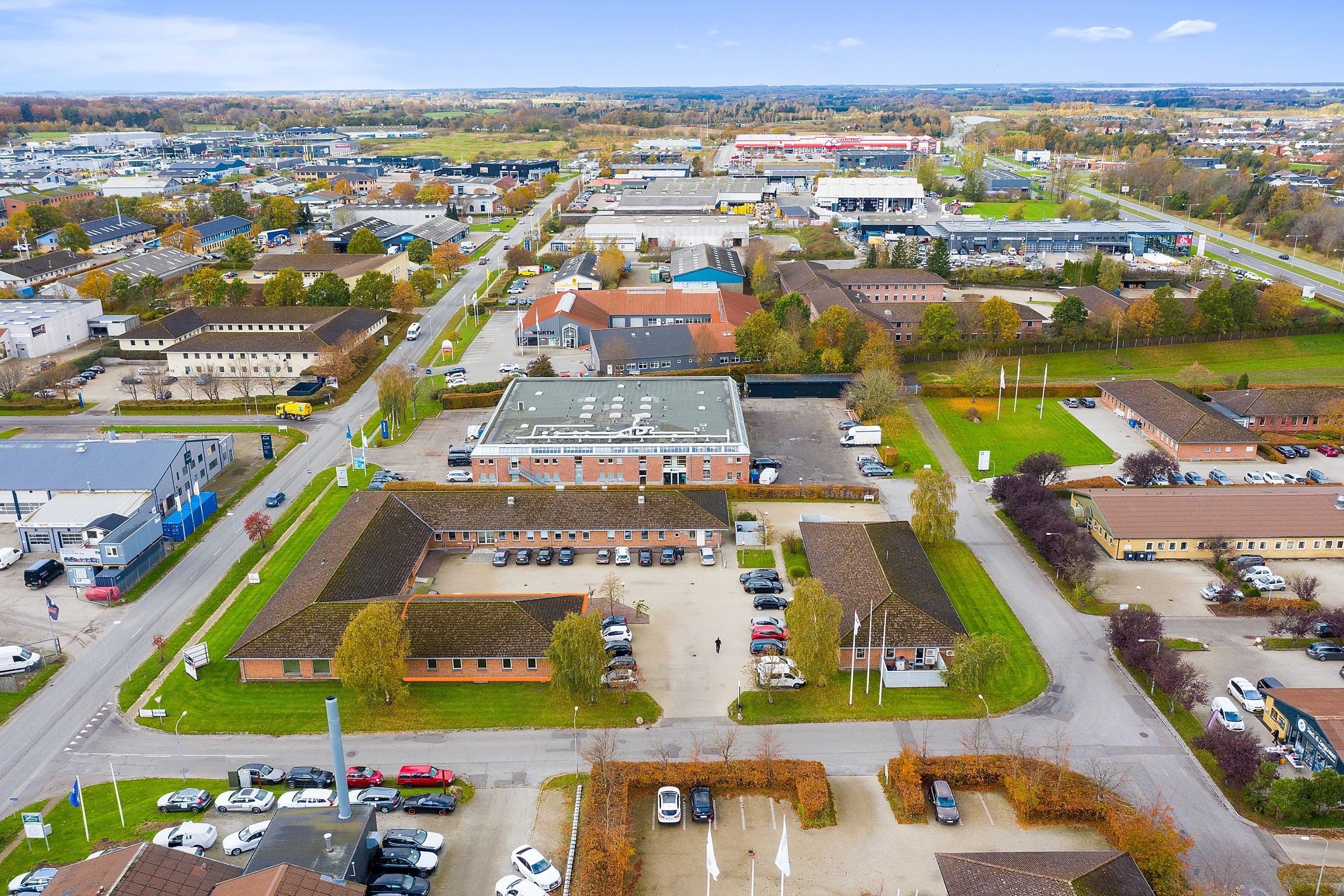 Kontorby i Herning med smukke parker, grønne områder og flotte bygninger samt biler parkeret i parkeringspladser og på gader