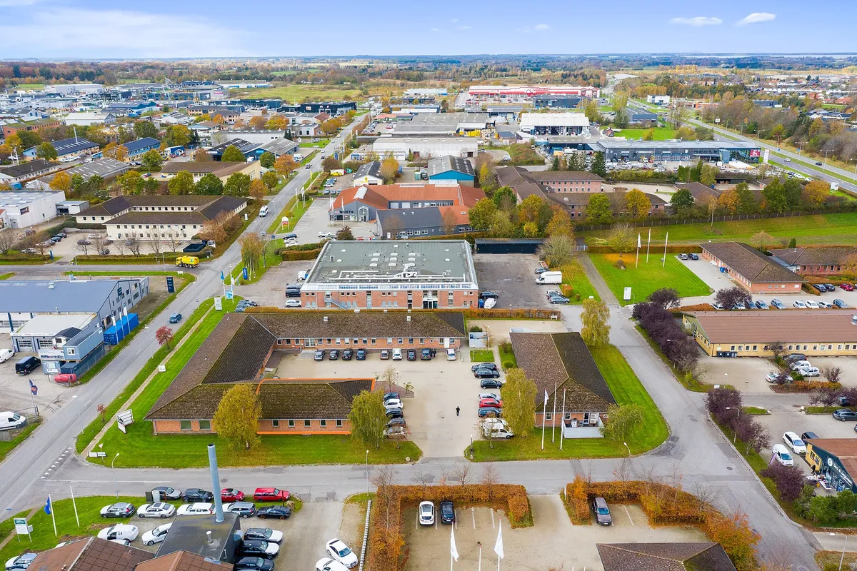 Kontorby i Herning med smukke parker, grønne områder og flotte bygninger samt biler parkeret i parkeringspladser og på gader