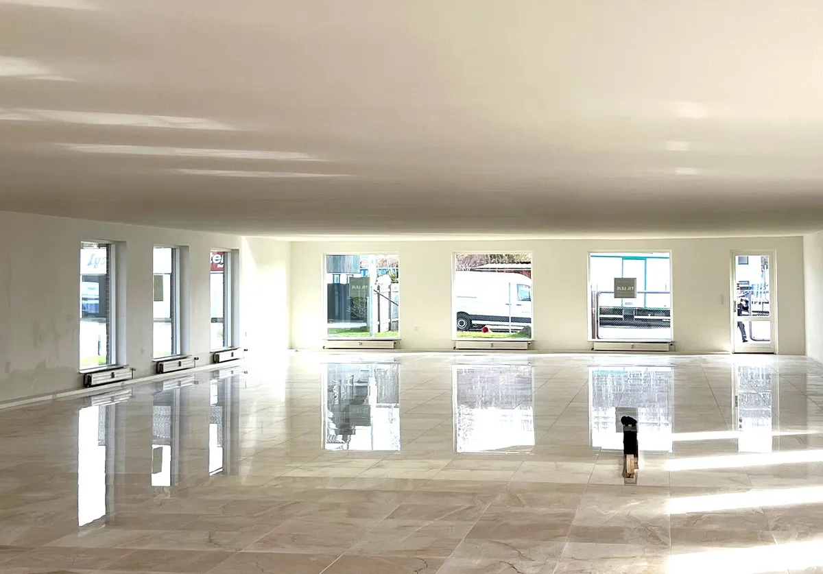 Indvendigt kontorlejemål med nyt køkken, toilet og store marmorfliser. Alle vinduer er åbne og refleksioner skabes på gulvet.