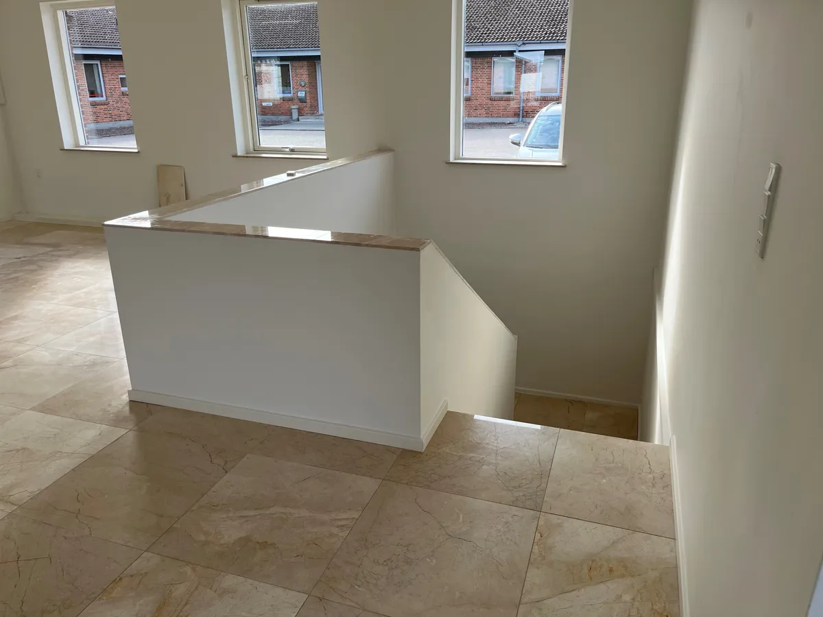 Store marmorfliser og nyt køkken i kontor med store vinduer og udsigt til parkeringsplads og biler