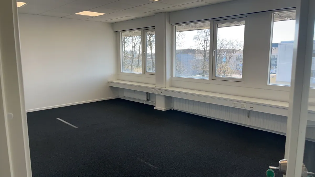 Trægulve, lyse og ren stue med vinduer mod gårdspladsen og højt til loftet