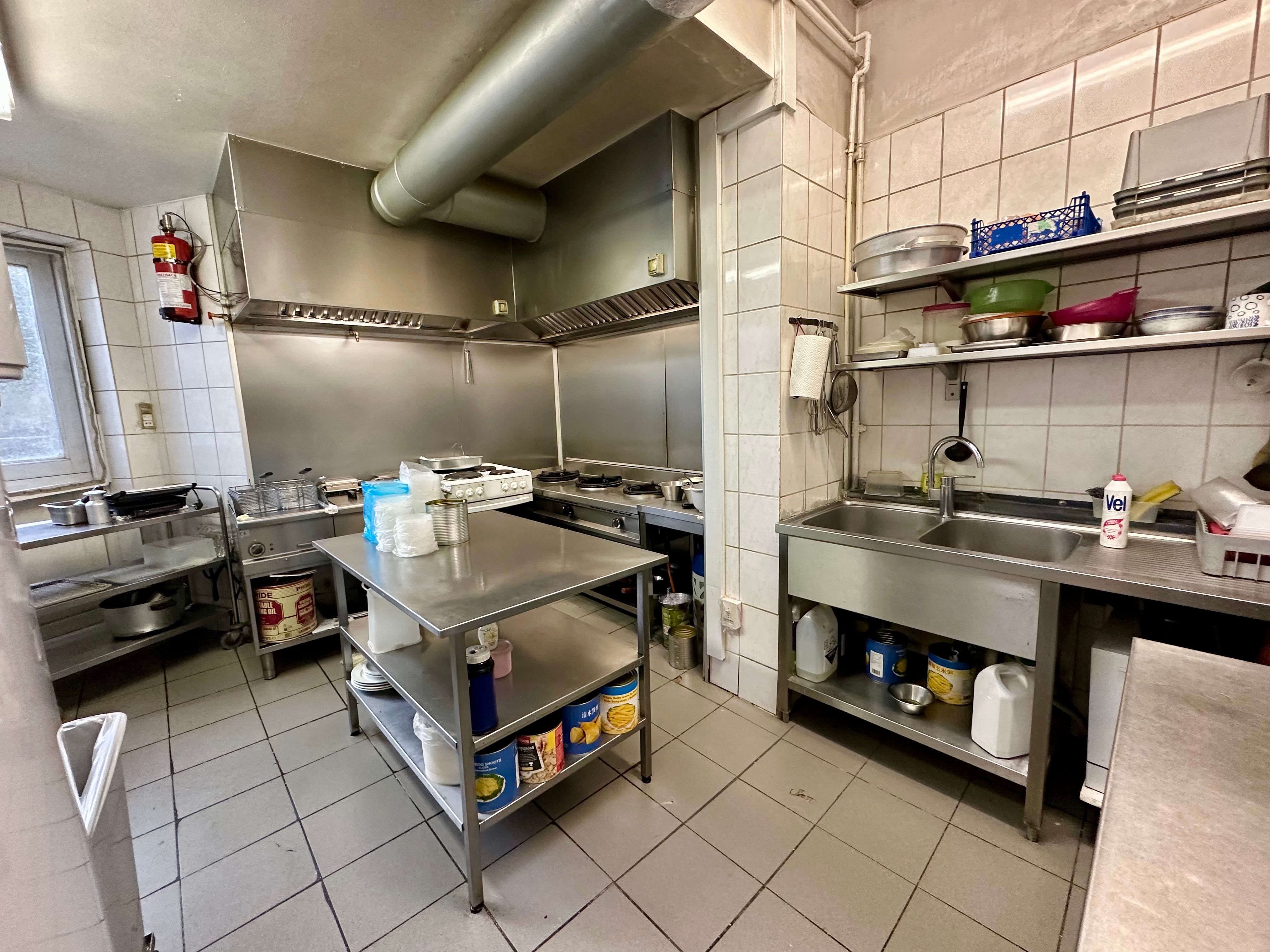 Produktionskøkken med moderne udstyr og opbevaringsrum, ren og funktionel indretning, strygejern, køkkengrej og