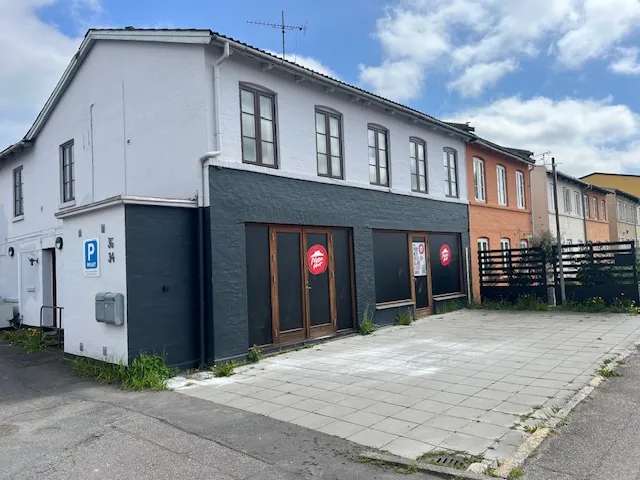 Pizza Hut i nyrenoveret lokale på 1. sal i hus med parkeringsplads foran og grønne buske.