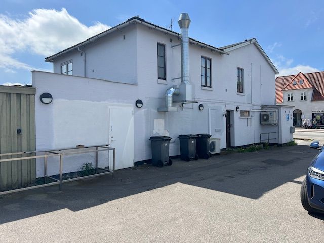 En nyrenoveret Pizza Hut restaurant med røgaffugter på taget og 3 skraldespande foran døren, samt en parkeringsplads med en