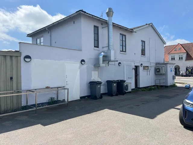 En nyrenoveret Pizza Hut restaurant med røgaffugter på taget og 3 skraldespande foran døren, samt en parkeringsplads med en