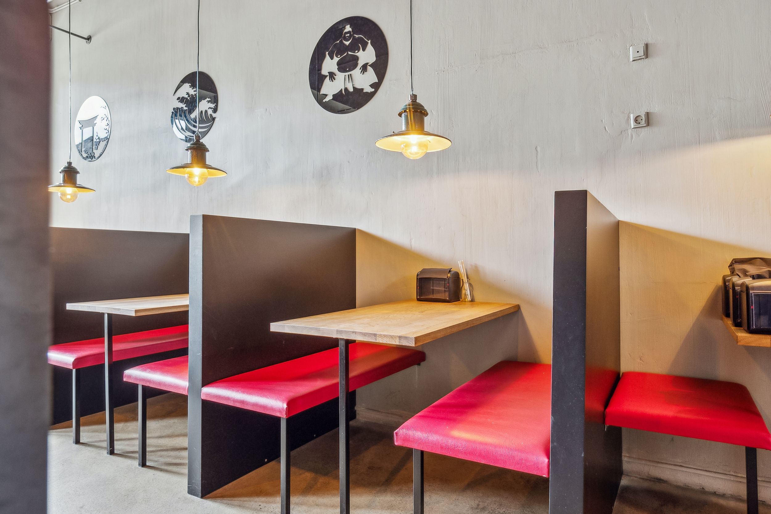 Indretning af et moderne restaurantbord med to røde stole, to store lysekroner og tre malerier på væggen