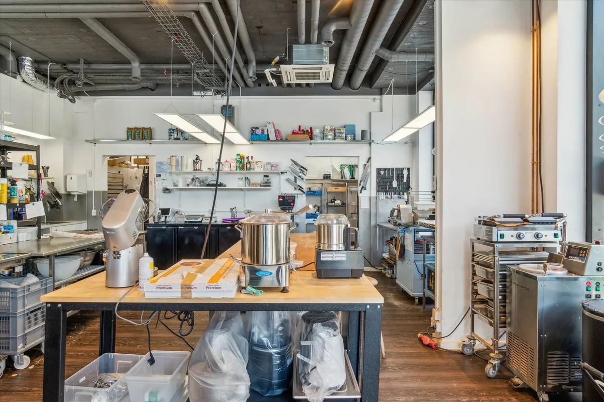 Erhvervslejemål med en stor køkken med moderne apparater og en lang træbord med flere kasser og plastikposer