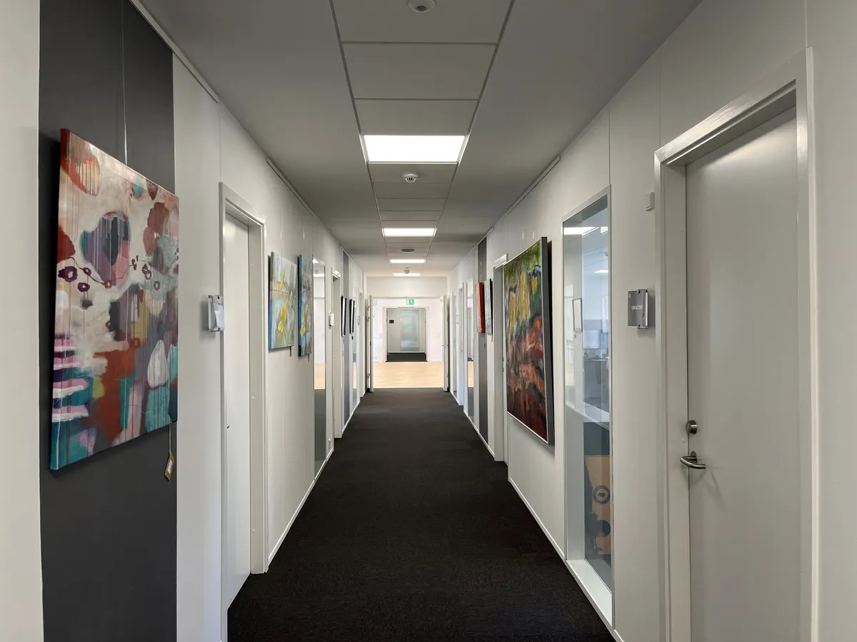 Hallen i et kontorfællesskab med farverige malerier på væggene og mørk gulvbelægning