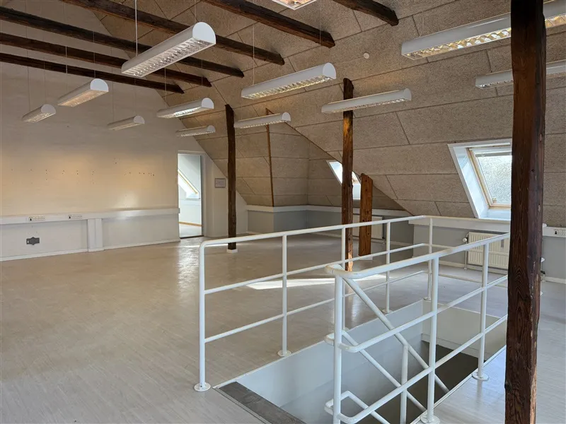 Lokaler i to etager med lyse lofter og lysekroner samt et hvidt stigeanlæg til opgang