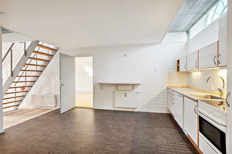 Moderne køkken med hvide vægge, åben dør, lyse lofter, radiatorer og en trappe for at stige op