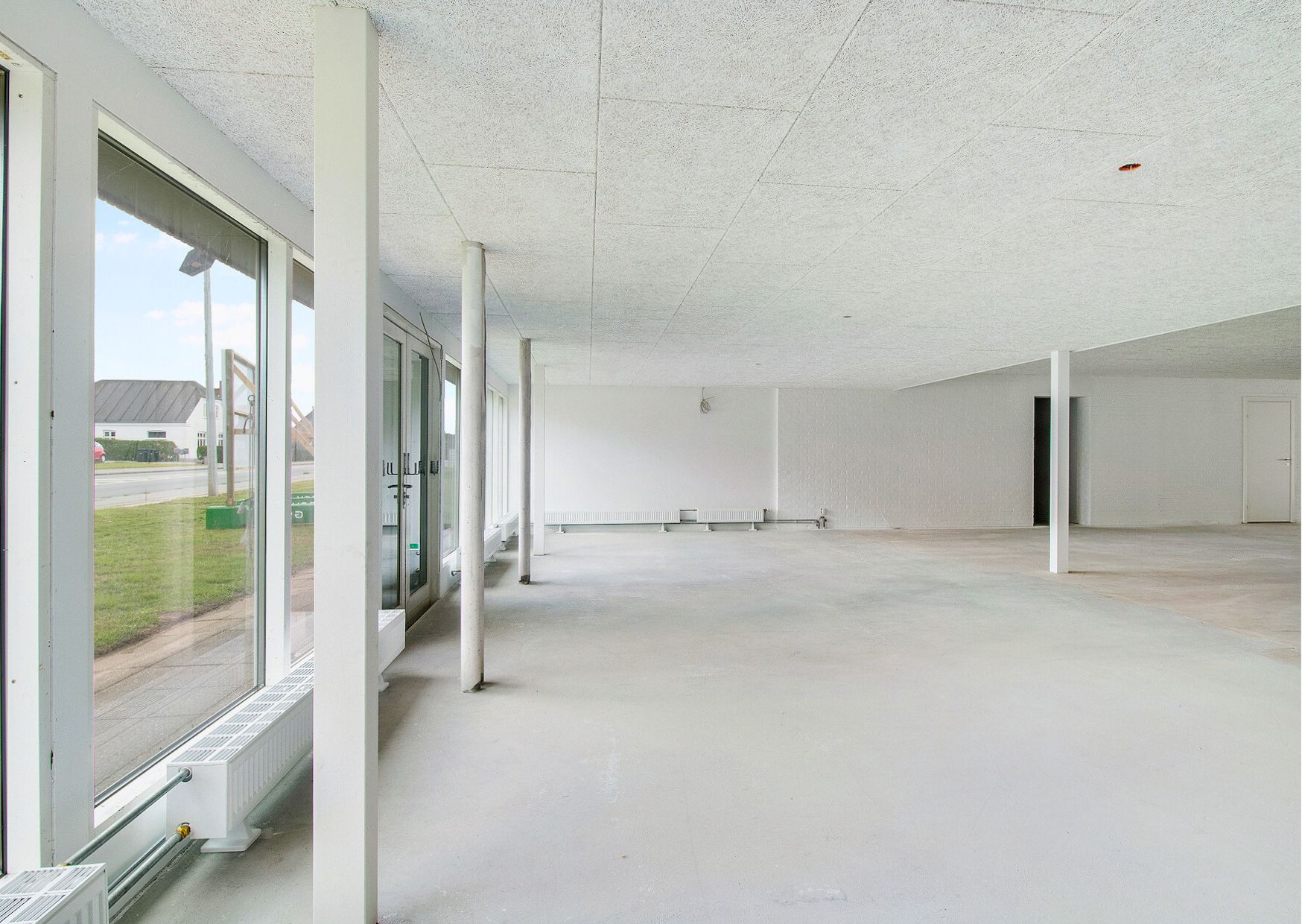 Store, hvide lokaler med store ruder og højt loft, radiatorer mod væggen og udgange i hver ende