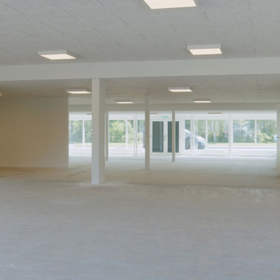 En stor, lys hall med højt til loftet, store vinduer og en lukket dør til venstre