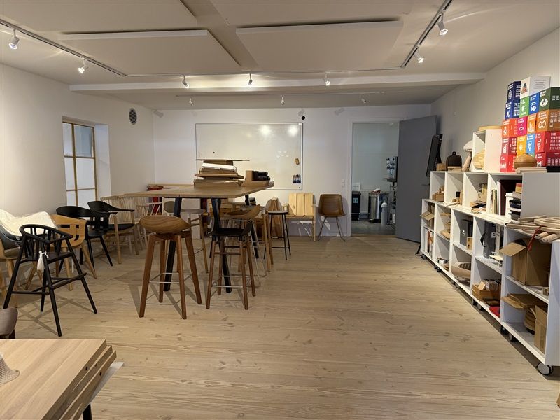 Moderne møbelforretning med trægulve, møbler, hylder og lysekroner i loftet