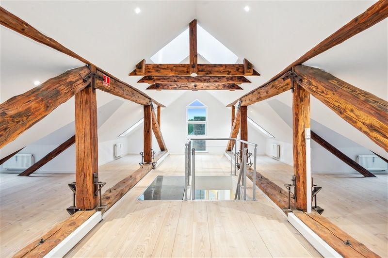 Moderne loftsrum med lyse loftsbjælker og åbent gulv og stige til loftet