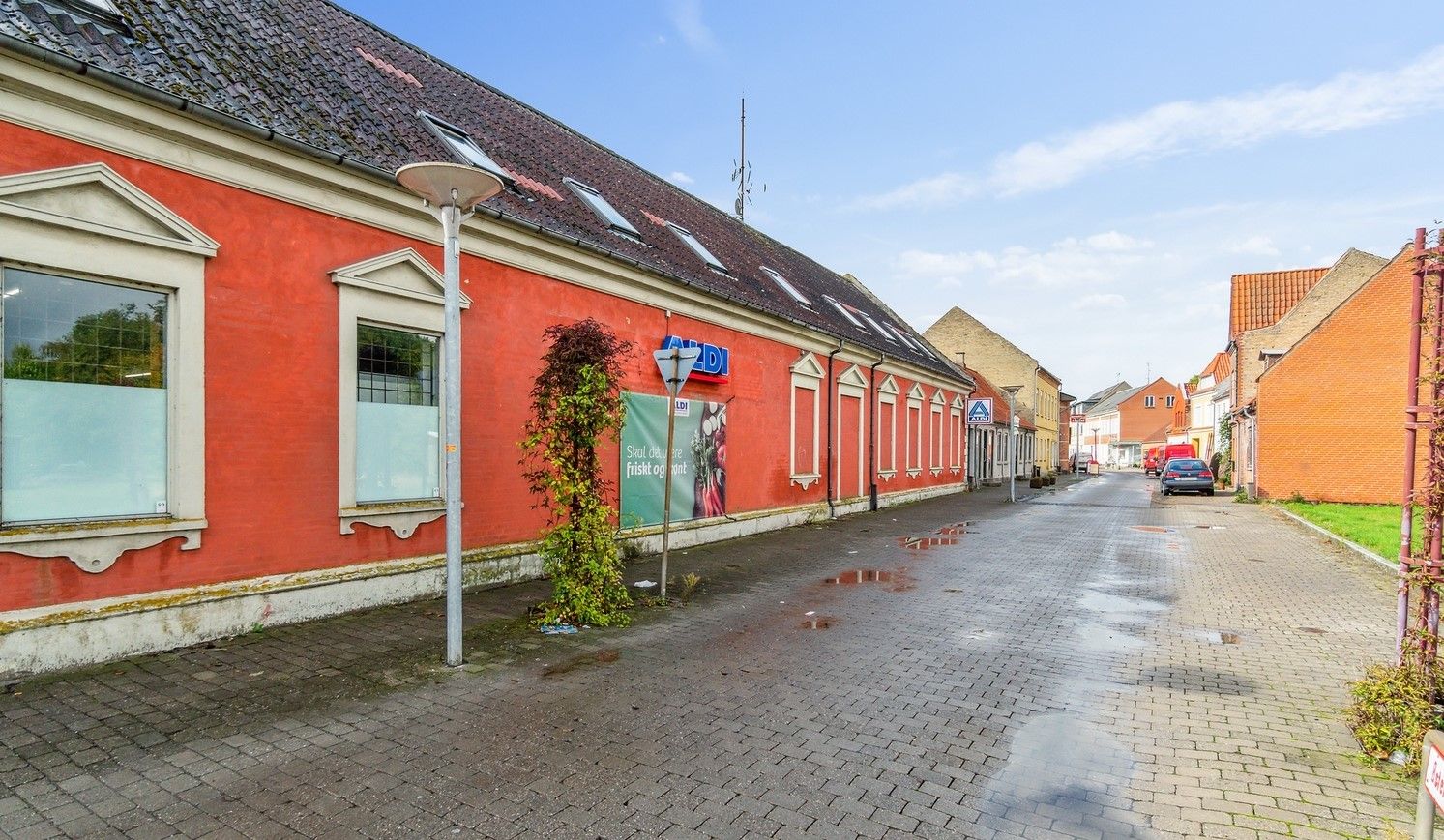 En rødmalet bygning med flere vinduer og en reklameskilt til Aldi