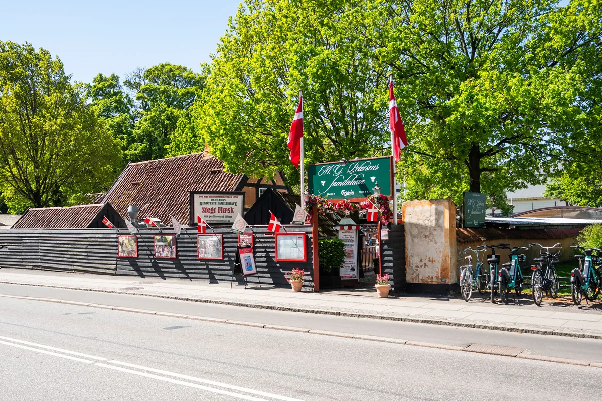 Historisk ølhave med mange cykler parkeret udenfor og gamle danske flag på facaden