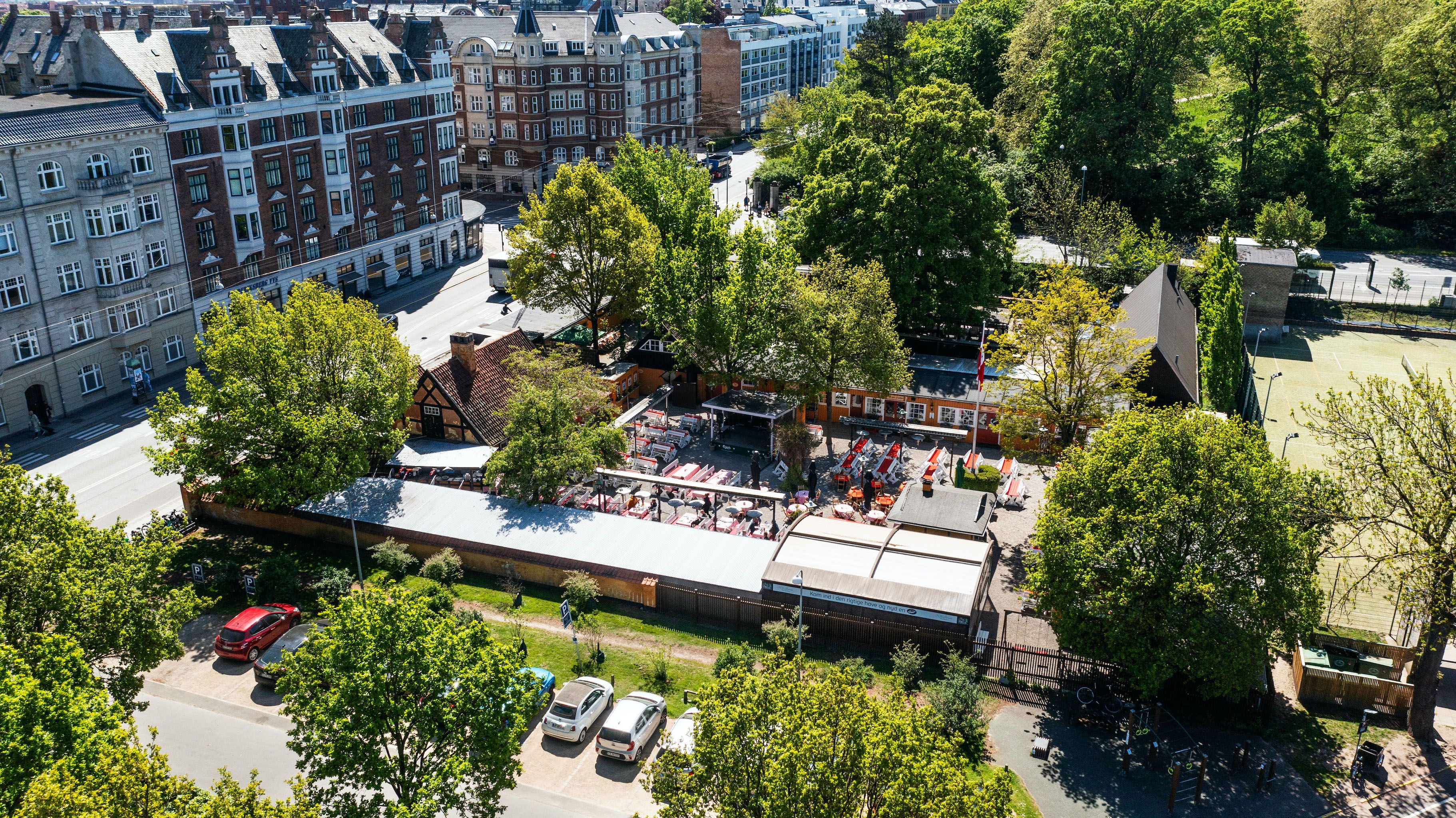 Restaurant i Frederiksberg med parkeringsplads, terrasse og spisesteder. Bygningerne og grønne områder omkring er lyse og