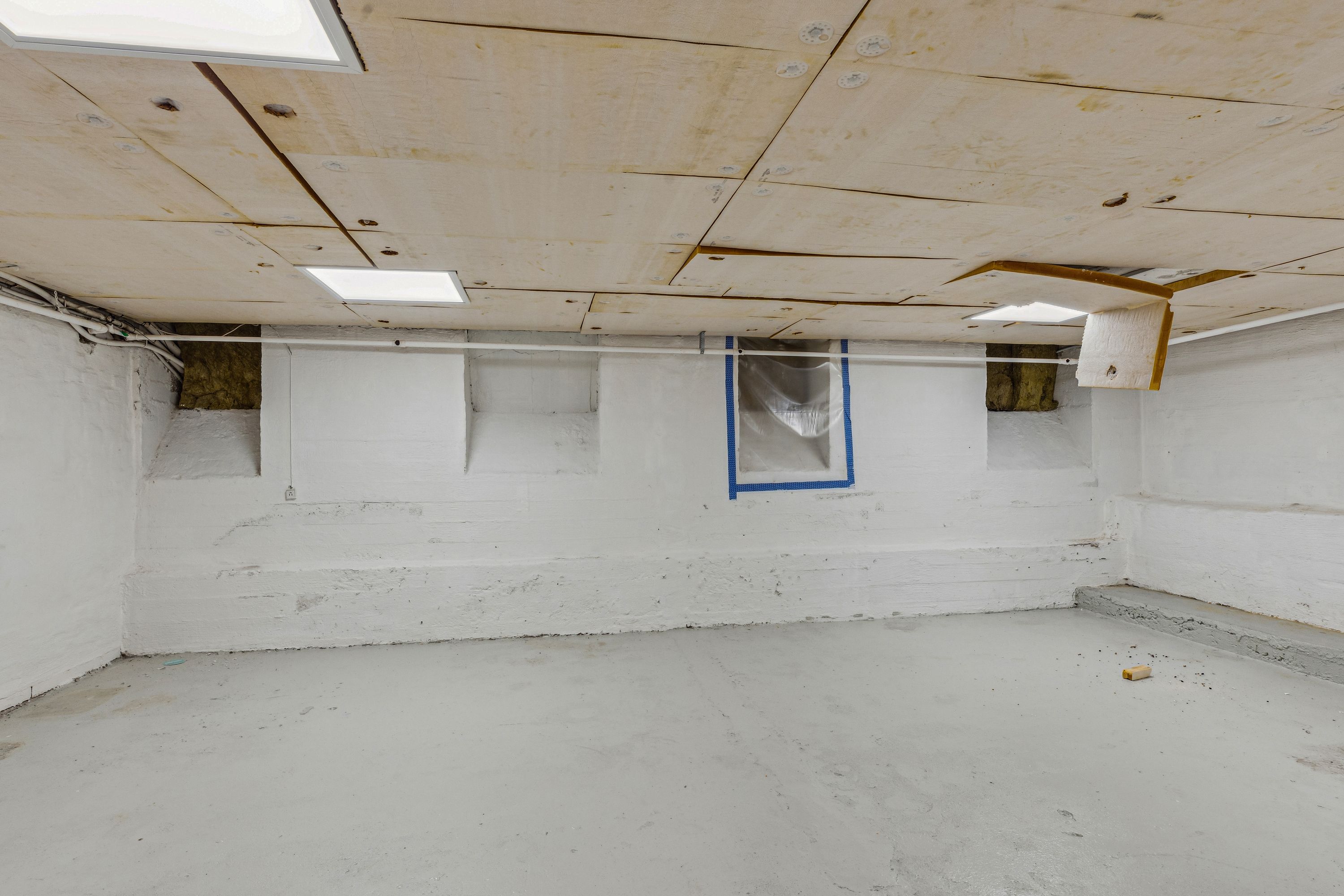 En tom værkstedslokal med hvide vægge og et hvidt loft med lysekroner og ventiler