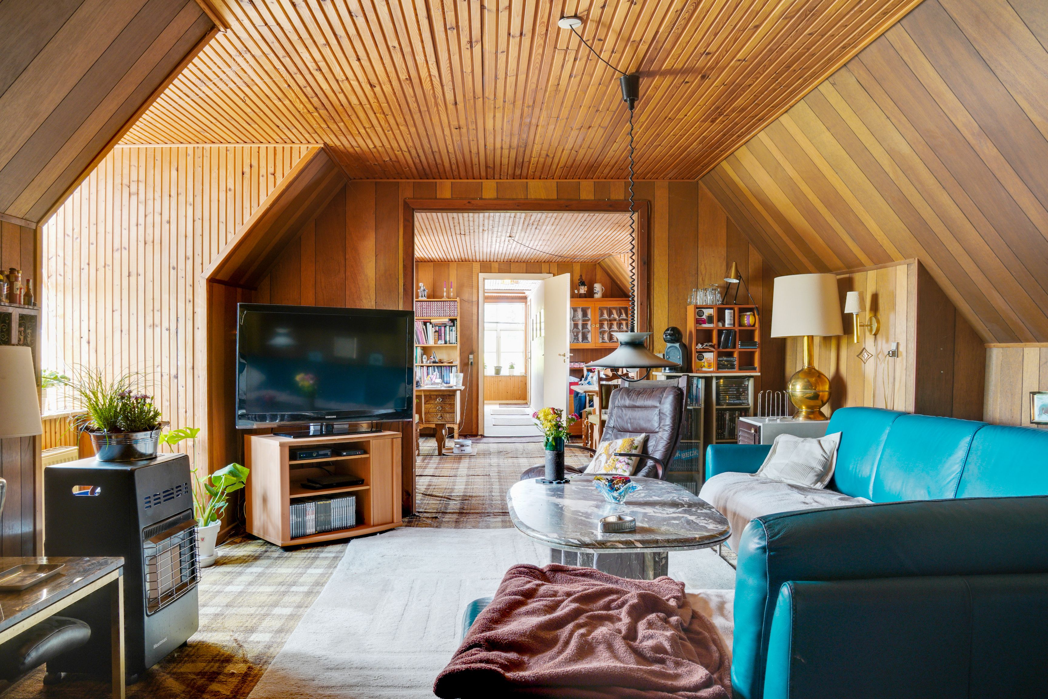 Et værelse med turkis sofa og tv samt en gulvlampe og en stålampe med lampeskærm