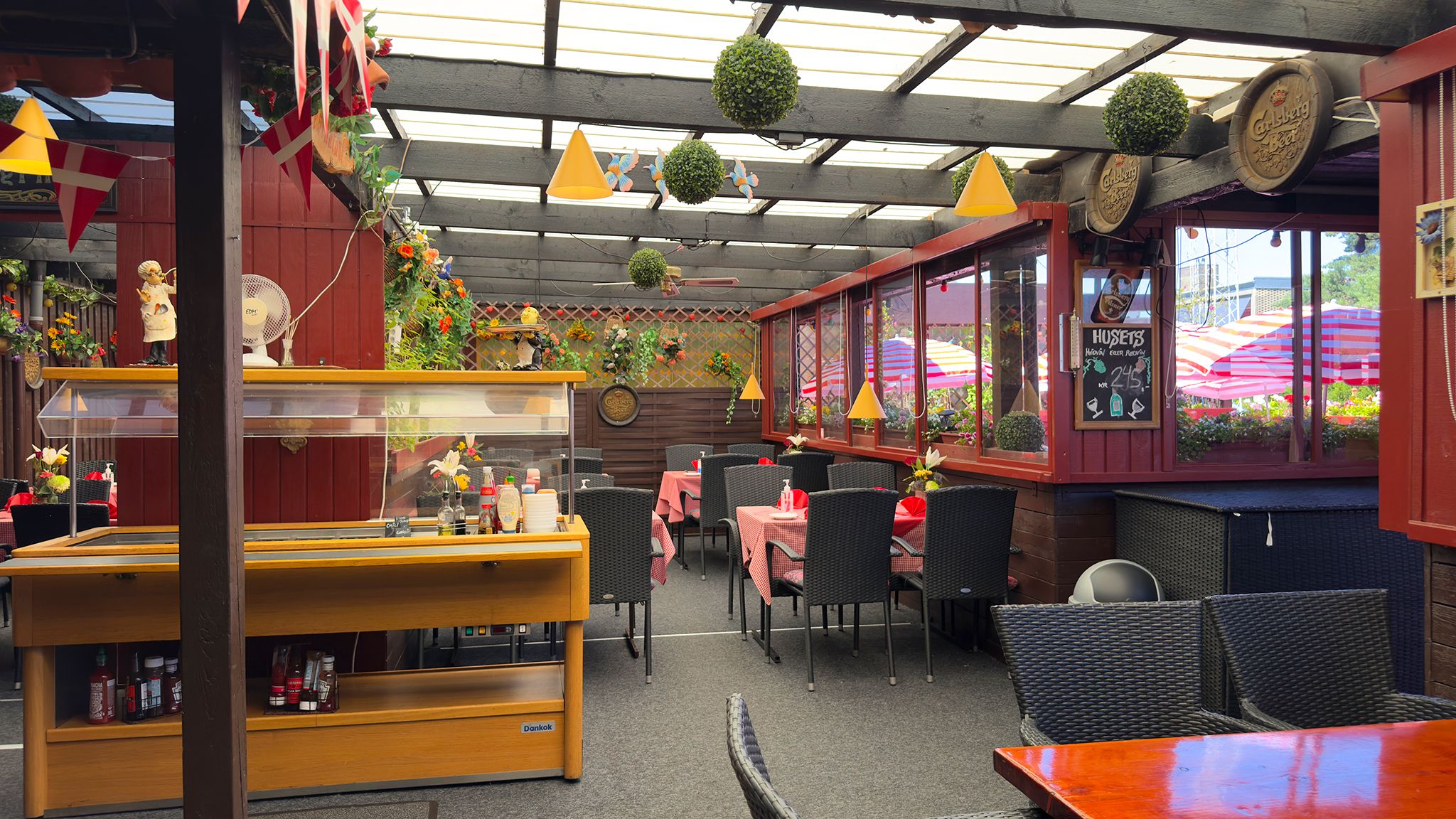 Inde i en restaurant med røde vægge og møbler samt en beskyttende overdækning med en række lysekroner og vinduer med